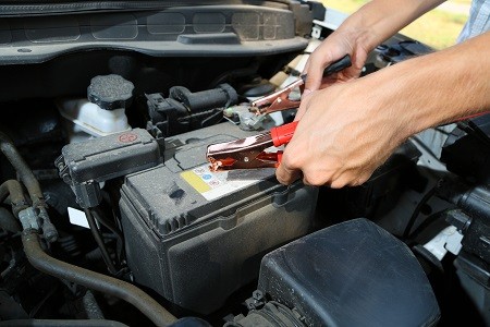 Car battery with jumper cables, indicating a potential battery issue causing starting problems