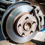 Worn car brake pads and rotor showing signs of rust and wear