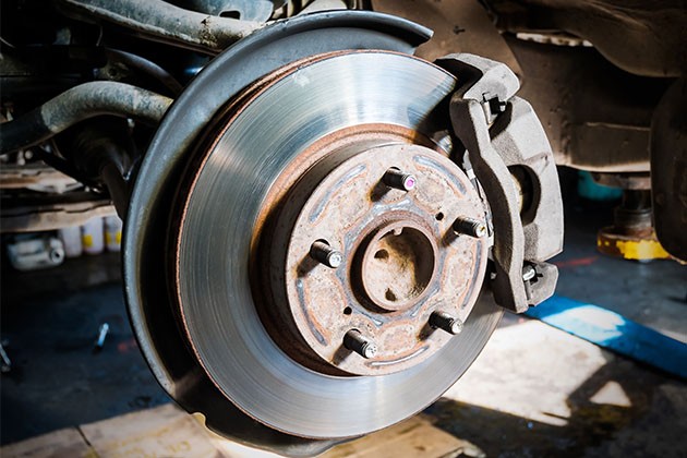 Worn car brake pads and rotor showing signs of rust and wear