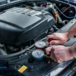 Man attaching cables to recharge car with Freon